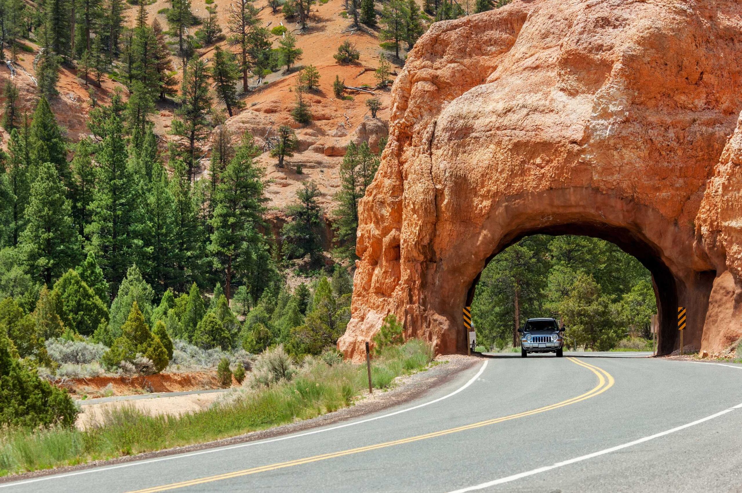 Car driving through Red Canyon in Utah, USA for header of American Road Signs and Road Markings.