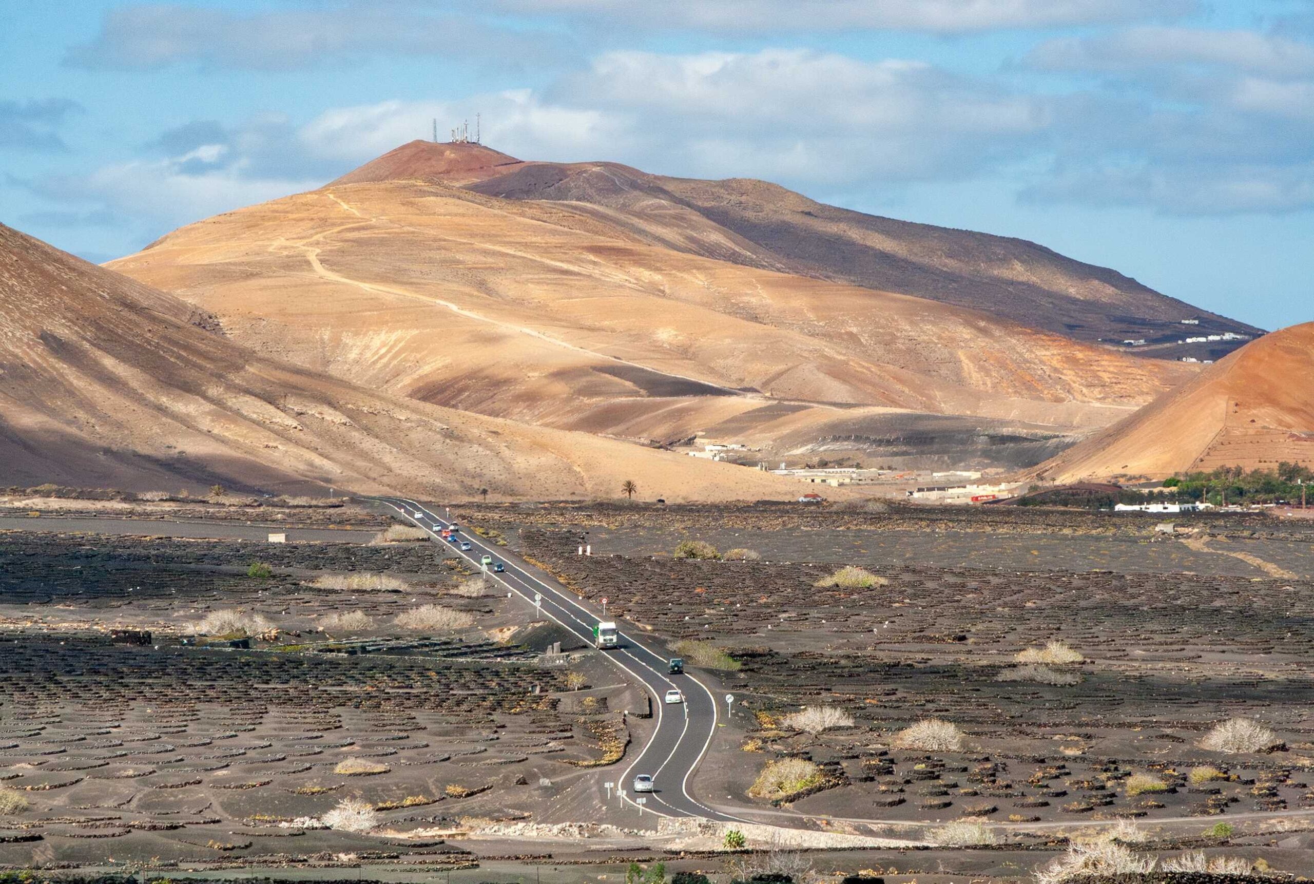 Scenic view to entrance of a national park in Lanzarote with cars in view to demonstrate importance of car rental excess insurance.