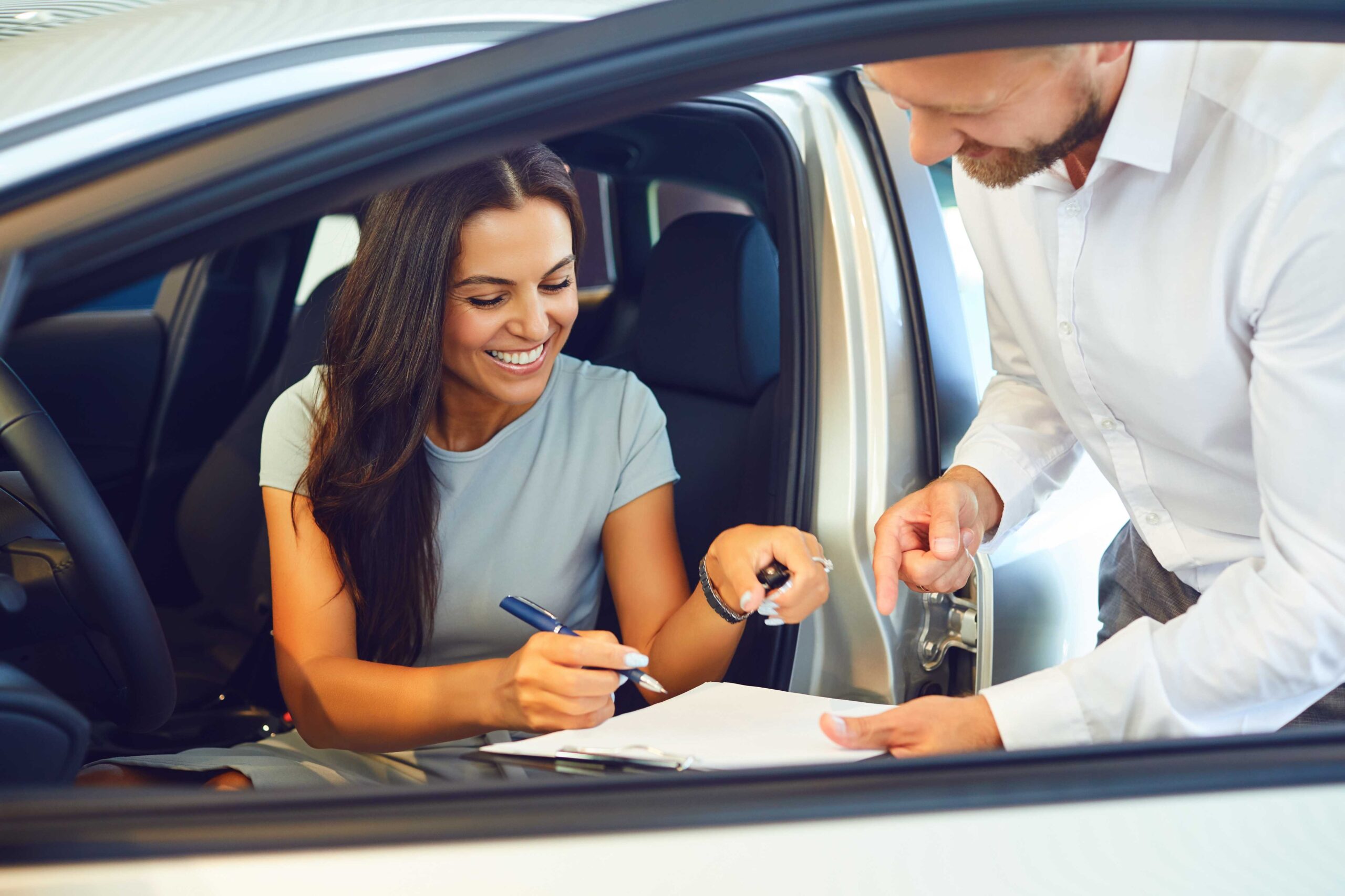 Woman sat in a car about to sign car hire agreement with car rental excess insurance.